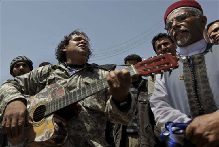 Amateur musician Massoud Abu Assir, 38, plays his guitar to entertain rebel fighters on the outskirts of Ajdabiya, Libya, Saturday, April 16, 2011. Assir's band was divided during the recent conflict after the bassist was captured by pro-Gadhafi forces, and the drummer continues to fight at the front line. (AP Photo/Ben Curtis)